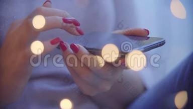 女人手使用手机智能手机，有五颜六色的灯光背景。 智能手机在女人手里。